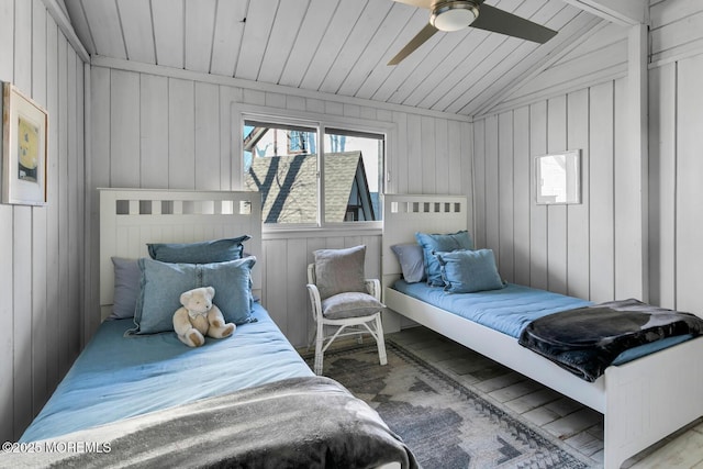 bedroom featuring ceiling fan, lofted ceiling, and wooden walls