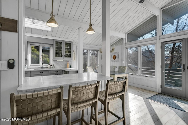 sunroom / solarium featuring lofted ceiling with beams and sink