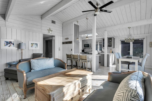 living room featuring ceiling fan, vaulted ceiling with beams, wood walls, and light hardwood / wood-style floors