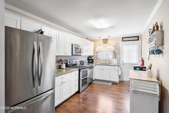 kitchen featuring backsplash, sink, white cabinetry, hanging light fixtures, and appliances with stainless steel finishes