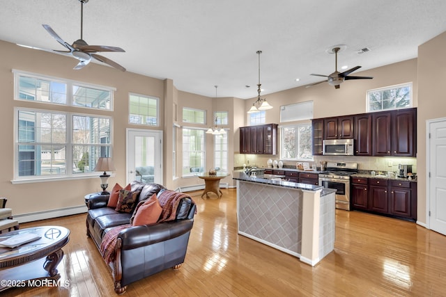 kitchen with tasteful backsplash, a baseboard heating unit, light hardwood / wood-style floors, pendant lighting, and appliances with stainless steel finishes