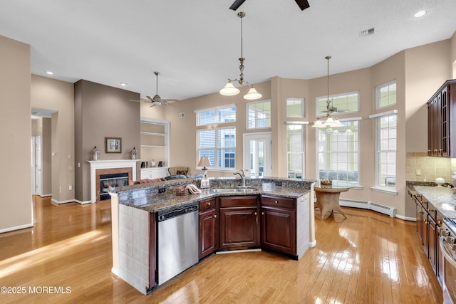 kitchen with decorative light fixtures, sink, stainless steel appliances, baseboard heating, and dark stone counters