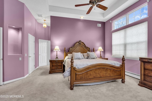 bedroom featuring ceiling fan, a baseboard heating unit, light carpet, and a tray ceiling