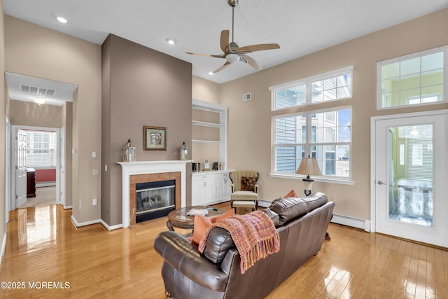 living room with a baseboard heating unit, ceiling fan, and light hardwood / wood-style flooring