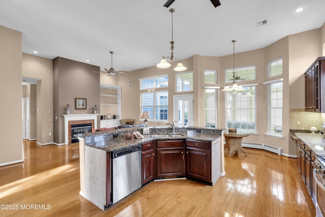 kitchen featuring baseboard heating, pendant lighting, appliances with stainless steel finishes, dark stone counters, and sink