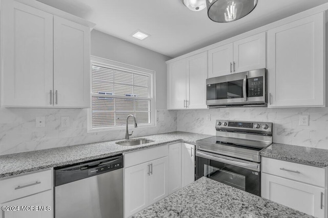 kitchen featuring tasteful backsplash, white cabinets, sink, and stainless steel appliances