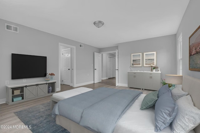 bedroom with ensuite bath and light hardwood / wood-style flooring