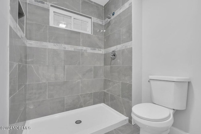 bathroom featuring toilet and a tile shower