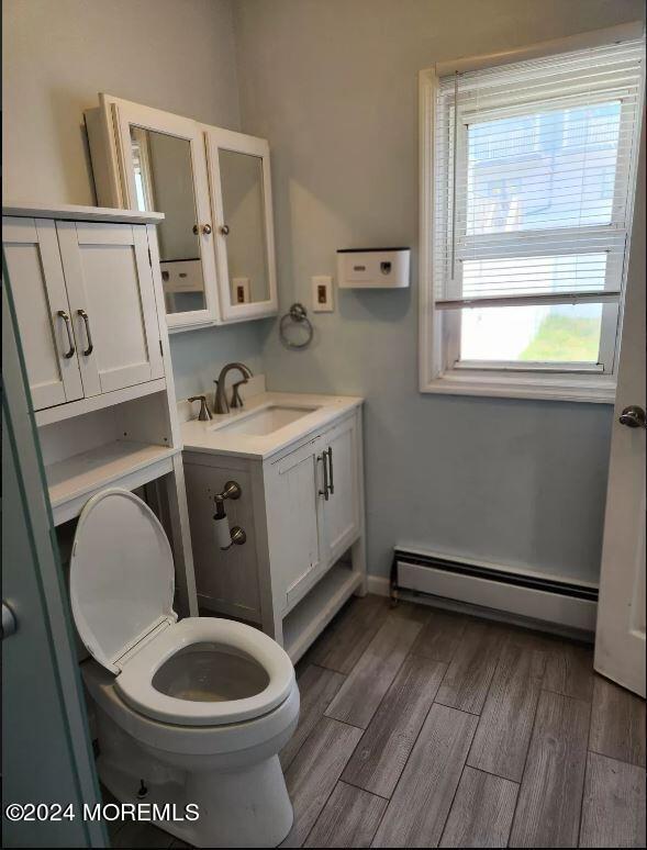 bathroom with toilet, vanity, and a baseboard radiator