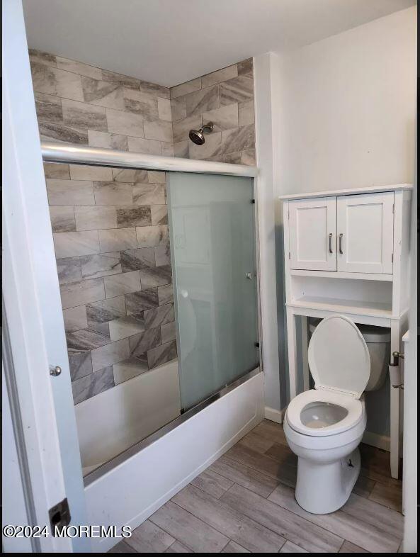 bathroom with shower / bath combination with glass door and toilet