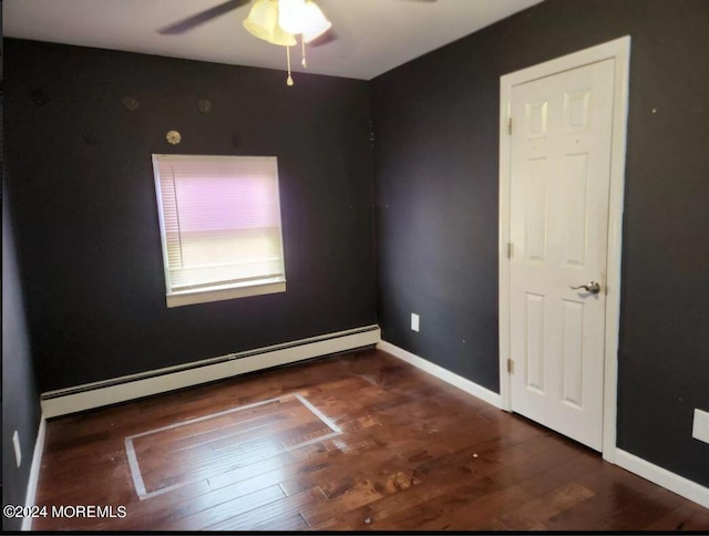 empty room featuring a baseboard heating unit, ceiling fan, and dark hardwood / wood-style floors