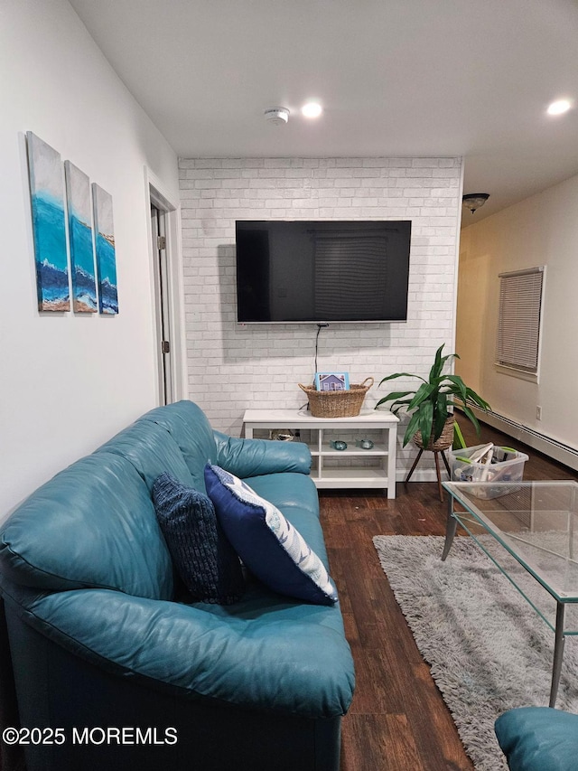 living room featuring dark wood-type flooring and brick wall