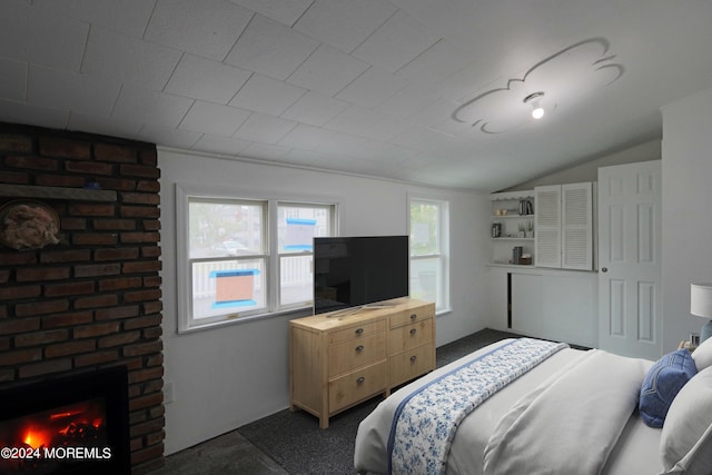 bedroom with vaulted ceiling and a fireplace