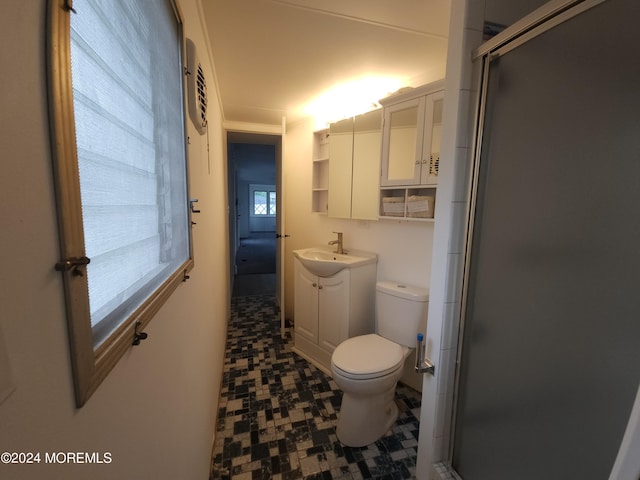 bathroom featuring a shower with shower door, vanity, and toilet