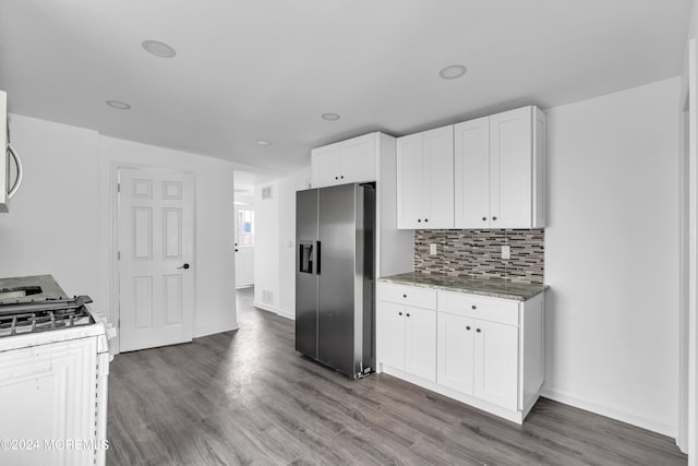 kitchen with hardwood / wood-style flooring, appliances with stainless steel finishes, decorative backsplash, light stone countertops, and white cabinets