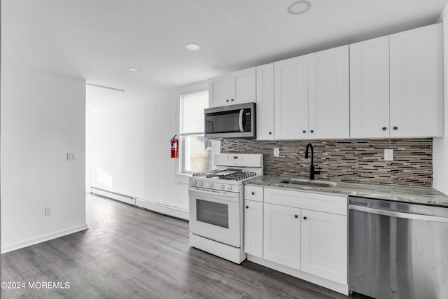 kitchen with sink, light stone countertops, stainless steel appliances, white cabinets, and baseboard heating