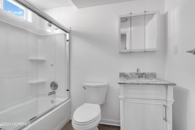 full bathroom with enclosed tub / shower combo, vanity, and toilet