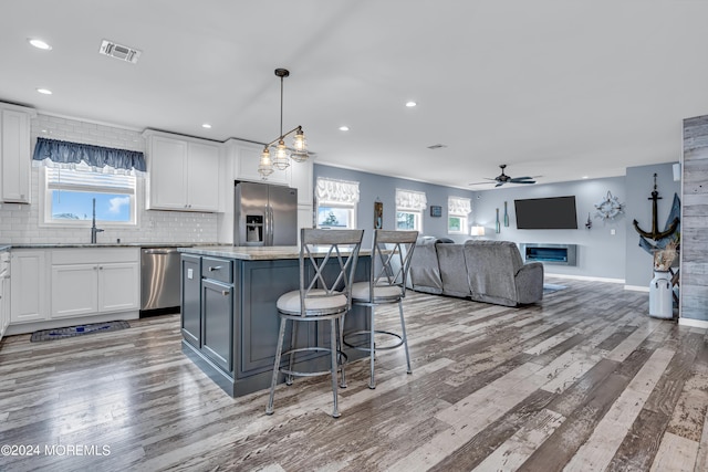 kitchen with decorative light fixtures, white cabinetry, stainless steel appliances, and a kitchen island