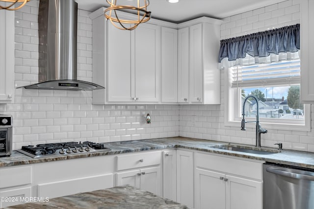 kitchen featuring white cabinetry, wall chimney range hood, stainless steel appliances, sink, and backsplash