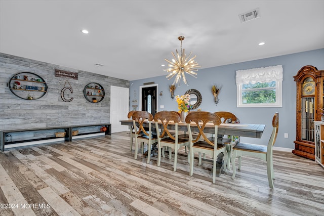 dining space with light hardwood / wood-style flooring, a chandelier, and wooden walls