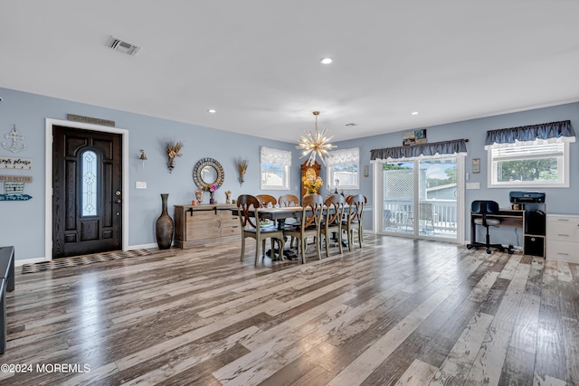 dining space with wood-type flooring and an inviting chandelier