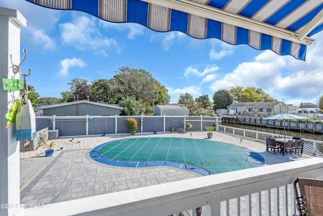 view of swimming pool featuring a water view and a patio area