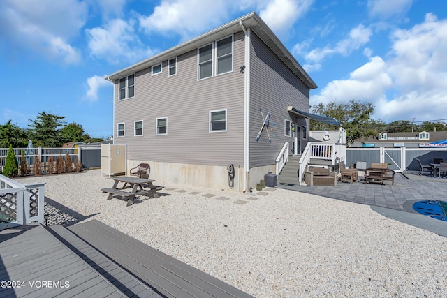 rear view of property with a patio area, a wooden deck, and a fire pit