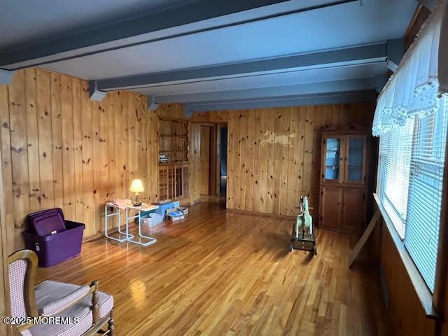 interior space with wood-type flooring, beam ceiling, and wooden walls