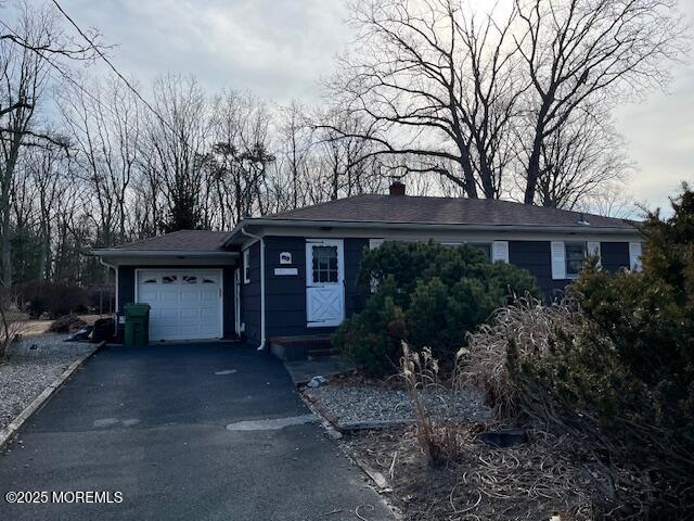 single story home featuring a garage, driveway, and a chimney