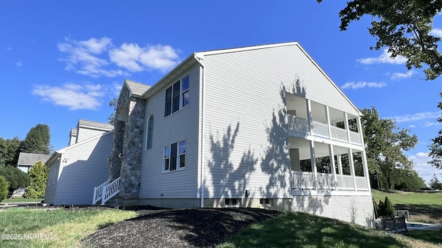 view of side of property with a lawn and a balcony