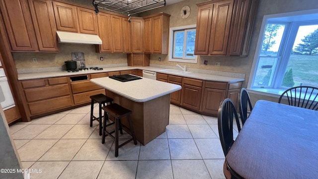 kitchen with light tile patterned floors, a center island, white appliances, a breakfast bar, and sink