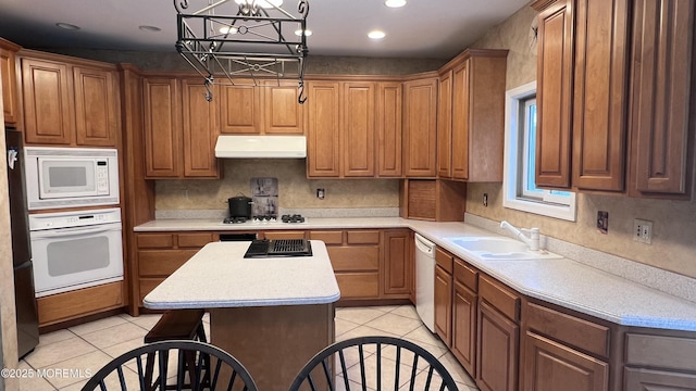 kitchen with white appliances, a kitchen island, an inviting chandelier, sink, and light tile patterned floors