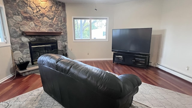 living room featuring wood-type flooring, a baseboard heating unit, and a stone fireplace