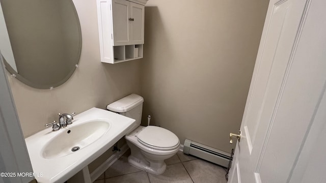 bathroom with baseboard heating, toilet, sink, and tile patterned flooring