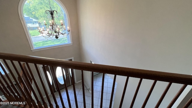 stairs with tile patterned floors and a chandelier