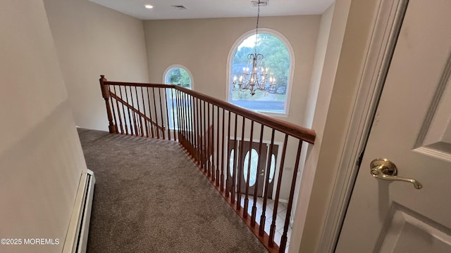 hallway featuring a baseboard heating unit, a notable chandelier, and carpet flooring