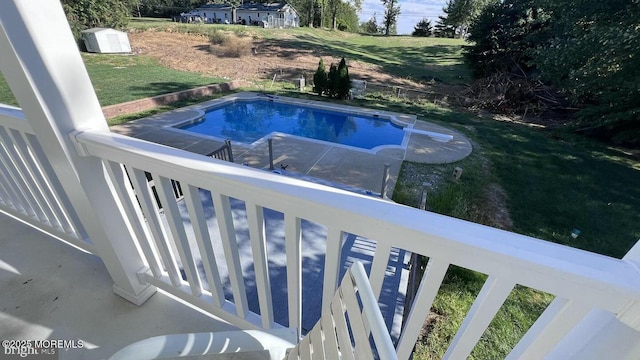 view of swimming pool with a storage unit and a yard