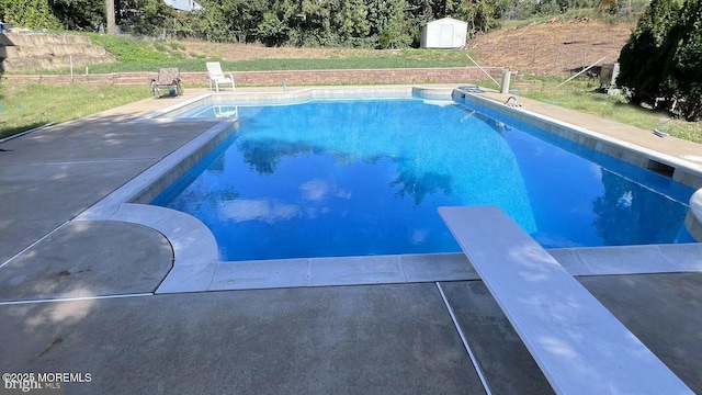 view of swimming pool featuring a diving board and a storage unit