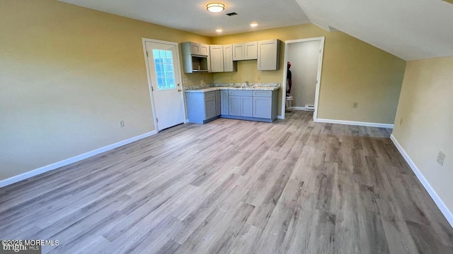 kitchen featuring sink, gray cabinetry, lofted ceiling, and light wood-type flooring