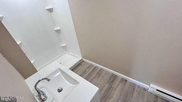 bathroom with a baseboard heating unit, hardwood / wood-style flooring, and sink