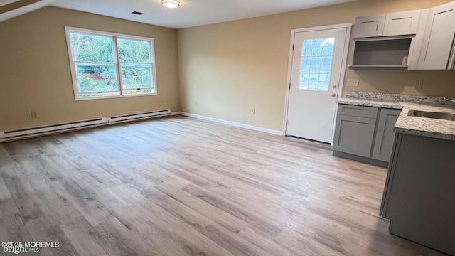 kitchen with baseboard heating, light stone countertops, light hardwood / wood-style floors, sink, and gray cabinetry