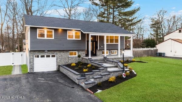 split foyer home with a front yard, covered porch, and a garage