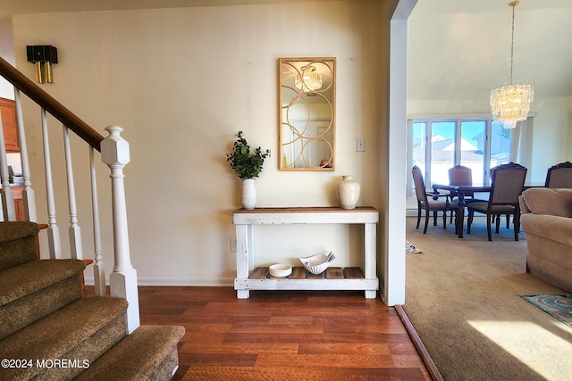 stairway with hardwood / wood-style flooring and a notable chandelier