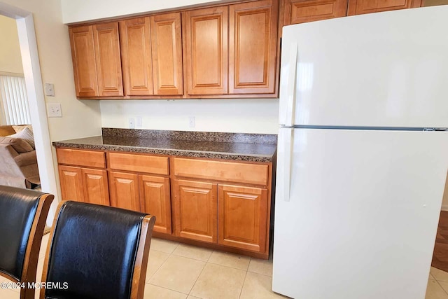 kitchen with light tile patterned floors and white refrigerator