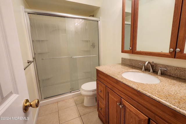 bathroom with toilet, tile patterned floors, vanity, and a shower with shower door