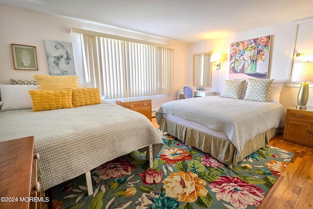 bedroom with baseboard heating and hardwood / wood-style flooring