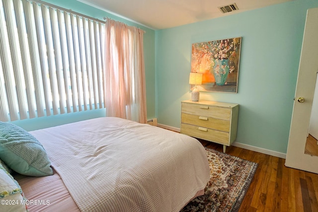 bedroom featuring a baseboard heating unit and dark hardwood / wood-style floors