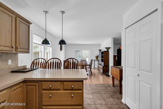 kitchen with kitchen peninsula, backsplash, and decorative light fixtures