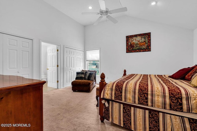 carpeted bedroom featuring ceiling fan, two closets, high vaulted ceiling, and ensuite bath