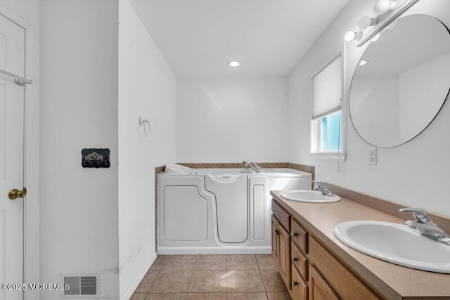 bathroom with tile patterned floors, a washtub, and vanity